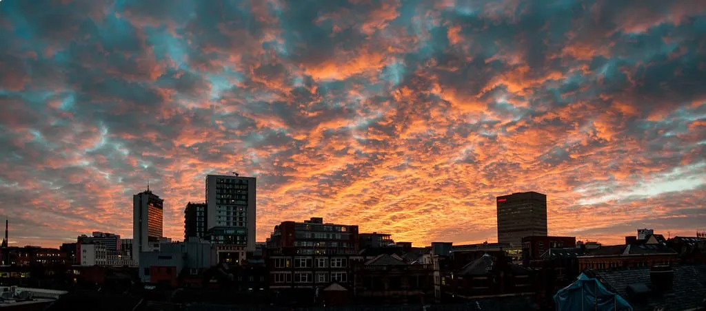 The Manchester skyline at sunset, seen across city rooftops