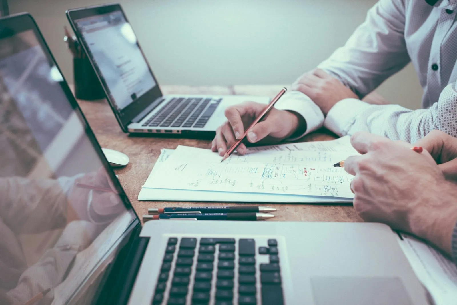 Two people working through a plan together at a desk with laptops and a printed worksheet
