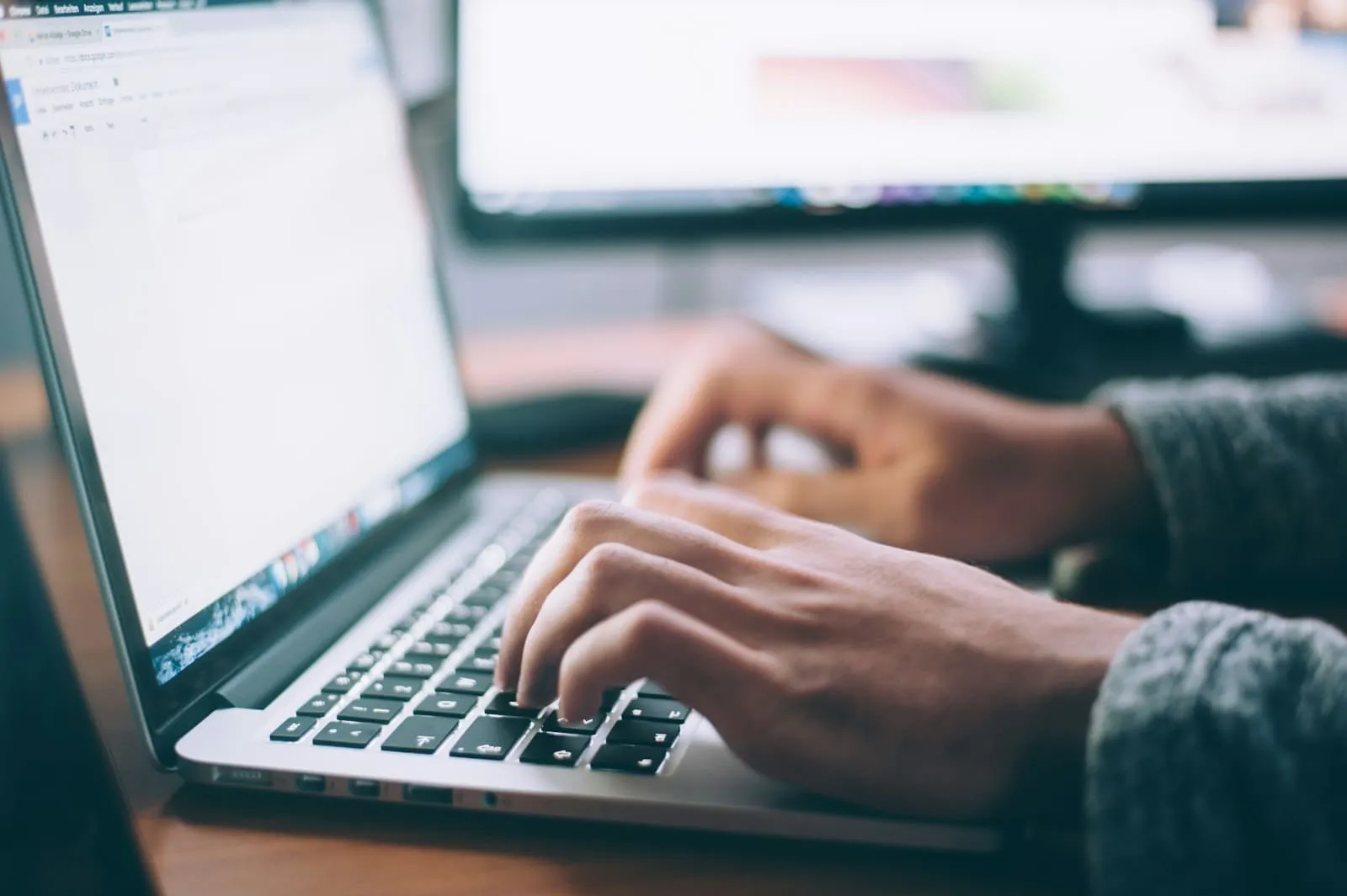 Hands typing on a laptop keyboard at a tidy desk